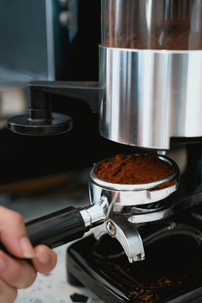 Close-up of coffee grinder dispensing grounds into portafilter, illustrating coffee preparation.